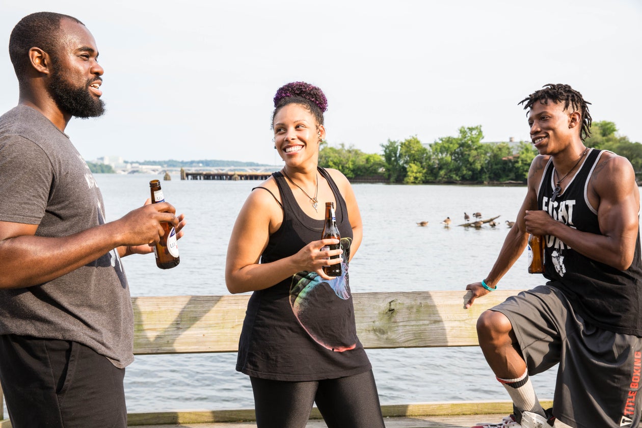 Friends sharing drinks by the water at sunset