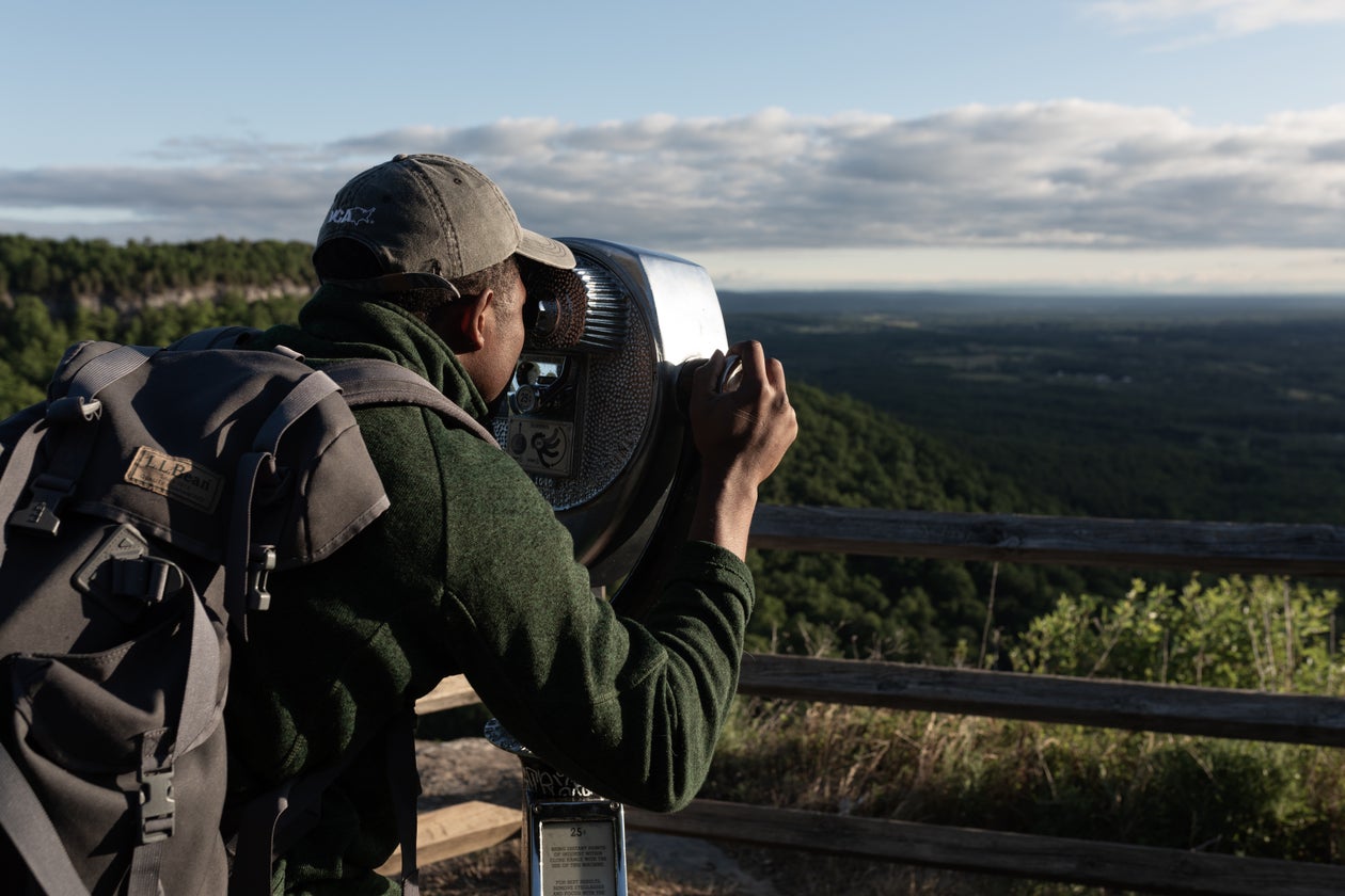 Traveler with a backpack pausing at a scenic viewpoint over the valley